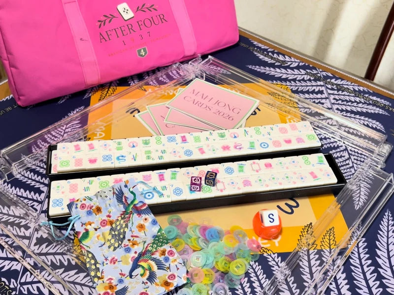 Mah jongg tiles, clear racks, dice, scoring chips, a pouch and reference cards laid out on a patterned mat