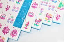 Close-up of Azure Tropics American Mah Jongg illustrated faces and layered blue edges