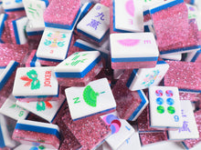 Scattered Pink Stardust American Mah Jongg tiles showing illustrated faces and pink glitter backs