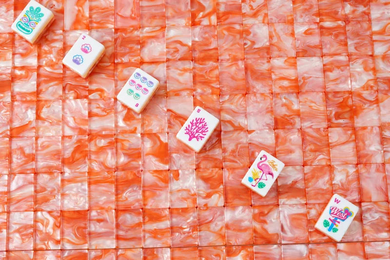 Colorful shell, coral, flamingo and West tiles arranged diagonally across orange pearlescent tile backs