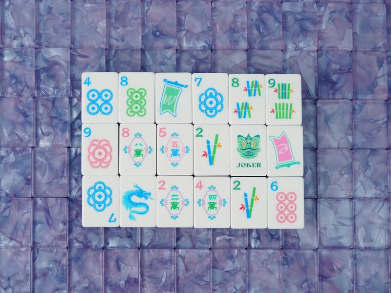 Eighteen face-up mah jongg tiles arranged on purple pearlescent backs, showing dots, bamboo, characters, a dragon and a Joker