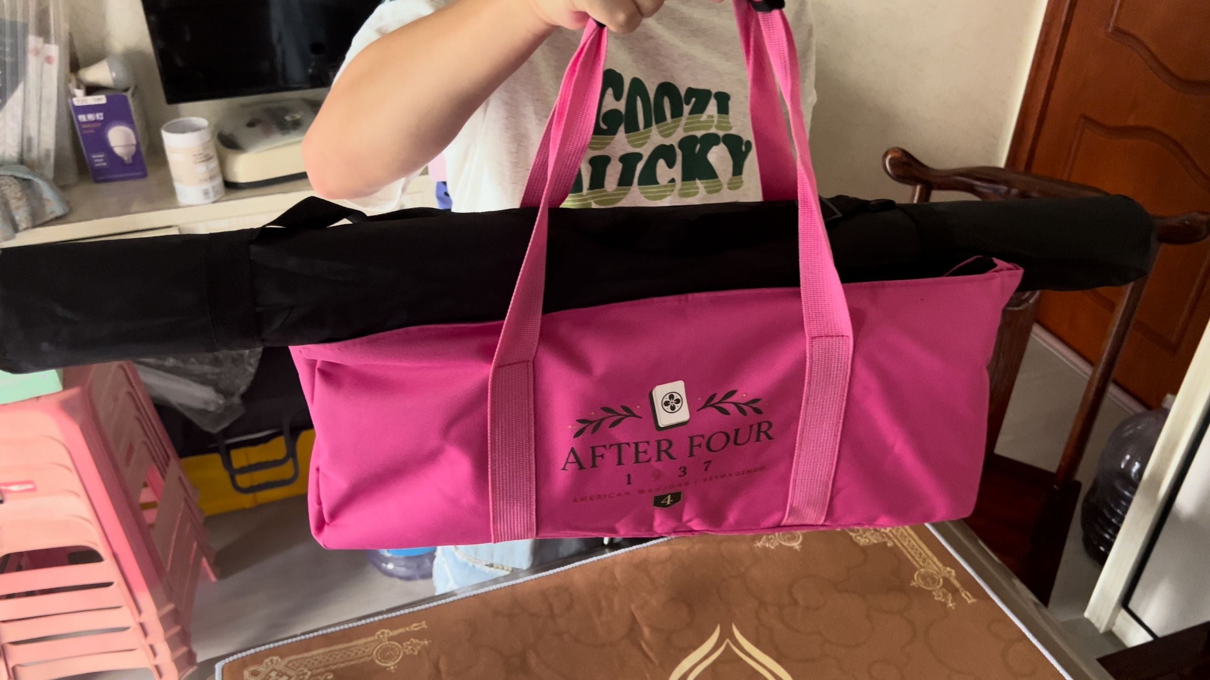 Packed pink AFTER FOUR carrying bag lifted by hand with coordinated rack sleeves ready to move